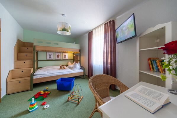 A child's bedroom with bunk beds, a desk, a chair, and a bookshelf. - Landhotel Salmen (Oberkirch)