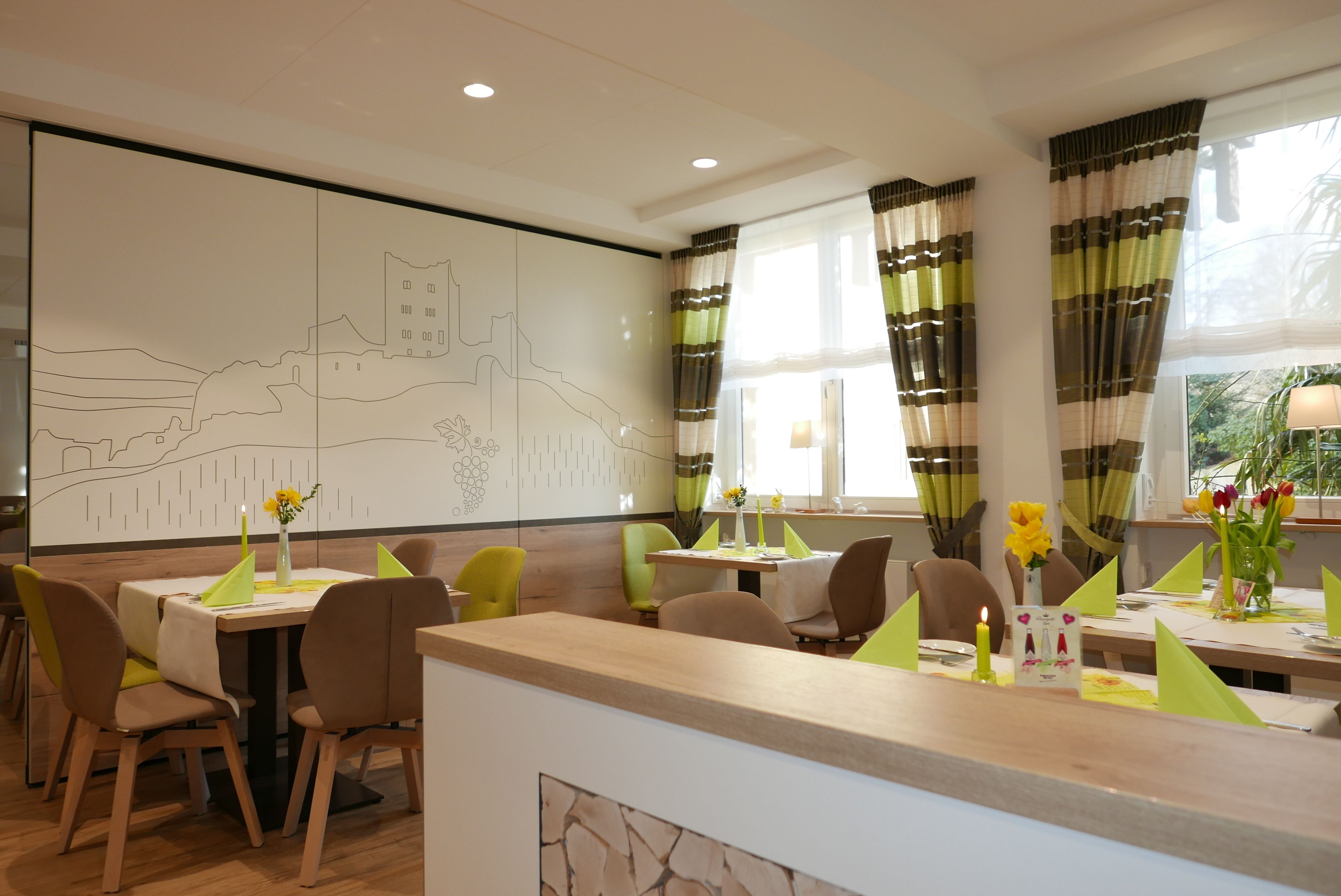 A dining area with tables, chairs, and a wall mural.