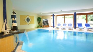 A swimming pool with lounge chairs, a small sailboat model, and a lighthouse model on the wall. - Landhotel Salmen (Oberkirch)