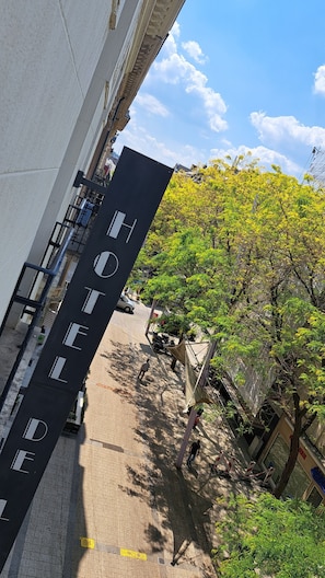 A hotel entrance with a sign reading "HOTEL" and a view of the street and trees.