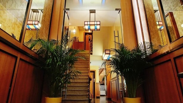 A grand lobby with a polished marble floor, a central staircase, and potted plants. - Hôtel de la Poste (Esch-sur-Alzette)