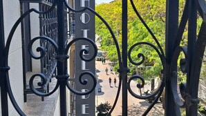 A balcony with wrought iron railings and a view of a street with pedestrians and greenery. - Hôtel de la Poste (Esch-sur-Alzette)