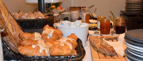 A buffet with various breads, pastries, and condiments.