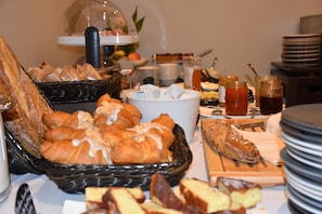 A buffet with various breads, pastries, and condiments.