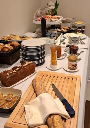 A buffet setup with various food items, plates, and utensils. - Hôtel de la Poste (Esch-sur-Alzette)