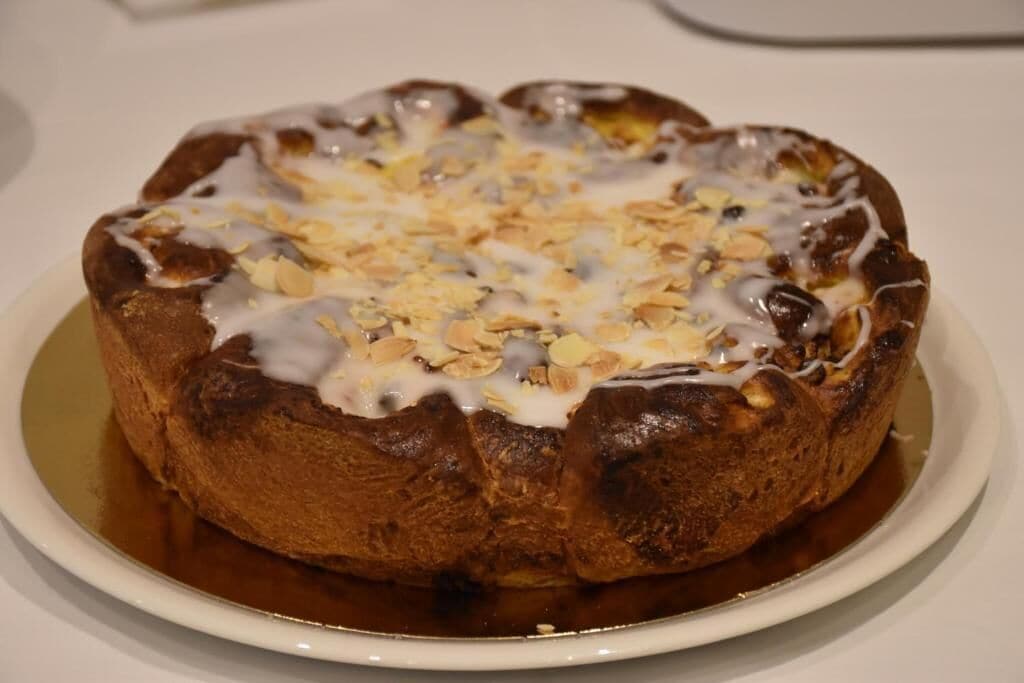 Un pastel redondo con cobertura brillante, posiblemente un glaseado, y espolvoreado con avena u otros ingredientes similares.