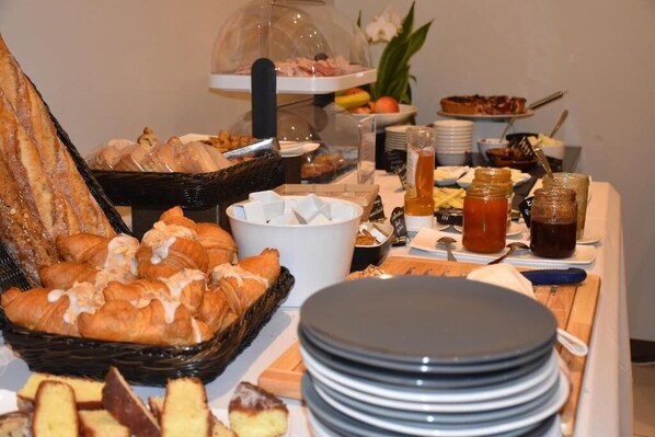 A buffet with various food items including pastries, fruits, and beverages.