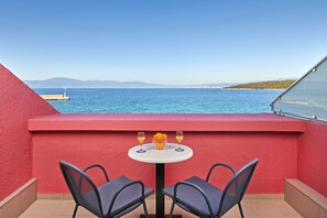 A balcony with a table and chairs, a view of the sea, and a distant island.
