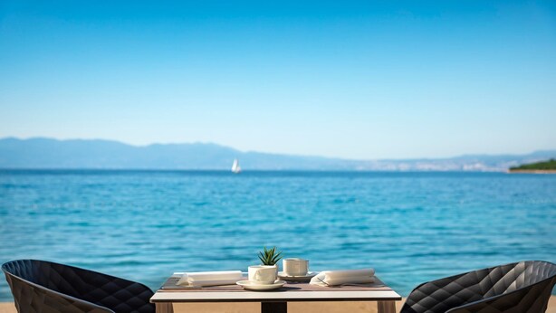 A table with a view of the sea and mountains in the background. - Veya Maradiso Hotel by Aminess  (Omisalj)