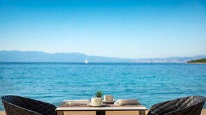 A table with a view of the sea and mountains in the background. - Veya Maradiso Hotel by Aminess  (Omisalj)