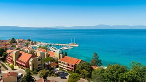 A coastal town with a marina, buildings with red roofs, and a clear blue sea. - Veya Maradiso Hotel by Aminess  (Omisalj)
