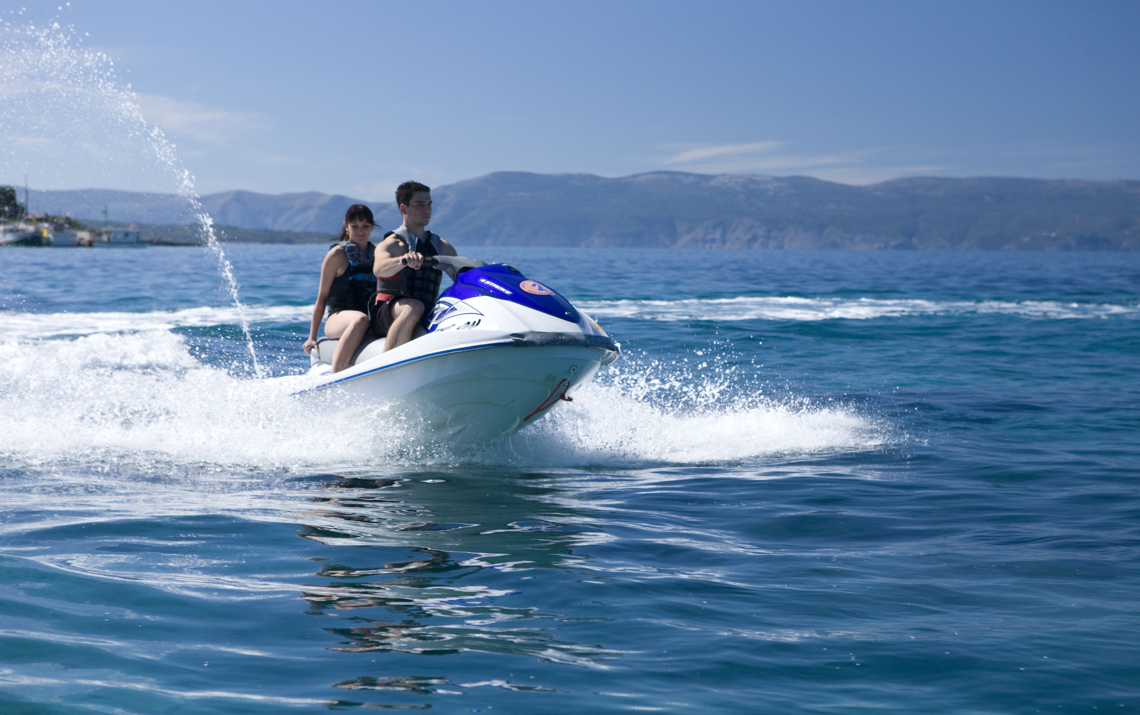 A speedboat with two passengers on a clear day.