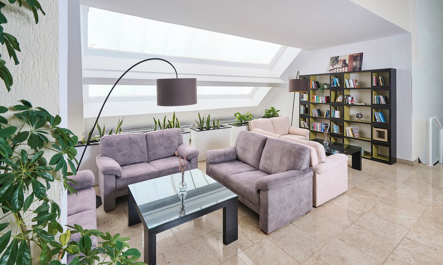 A modern living room with a sofa set, a coffee table, a floor lamp, and a bookshelf.
