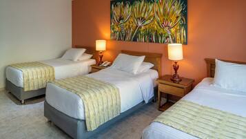 A hotel room with two single beds, a double bed, and a painting on the wall.
