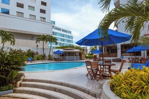 A pool area with steps leading to the pool, surrounded by palm trees and blue umbrellas. - Hotel Arena Blanca (San Andrés)