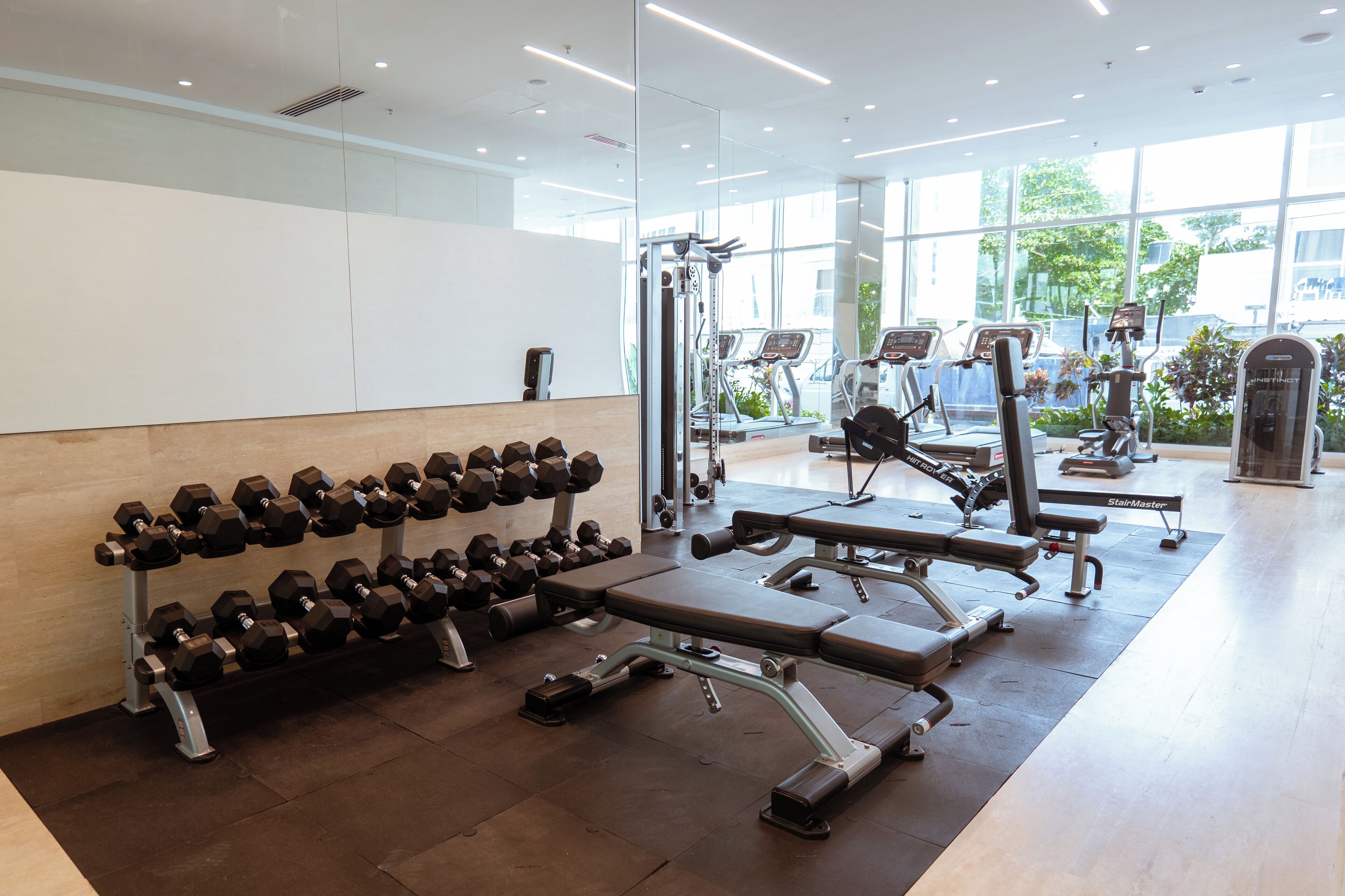 A gym with exercise equipment, a bench, and a rack of dumbbells.