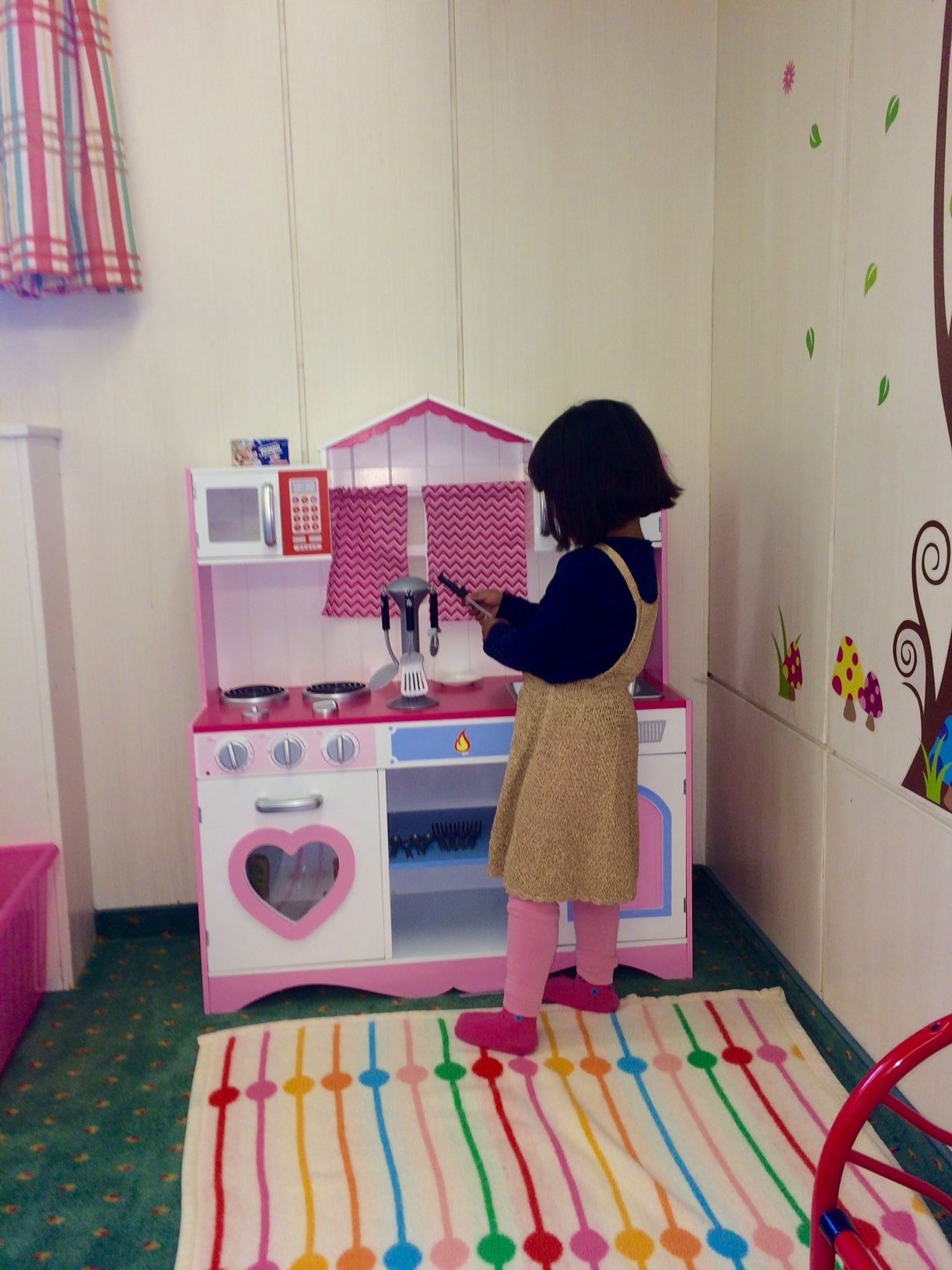 A child playing with a toy kitchen set.
