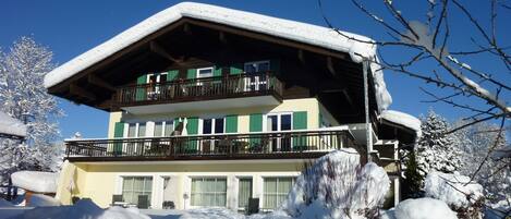 Un bâtiment à deux étages, avec un toit et un balcon couverts de neige.