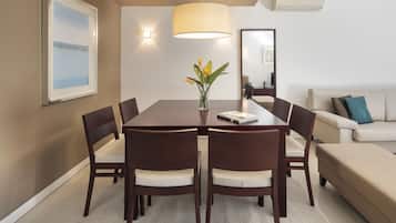 A dining area with a table, chairs, a vase with flowers, a lamp, and a sofa.
