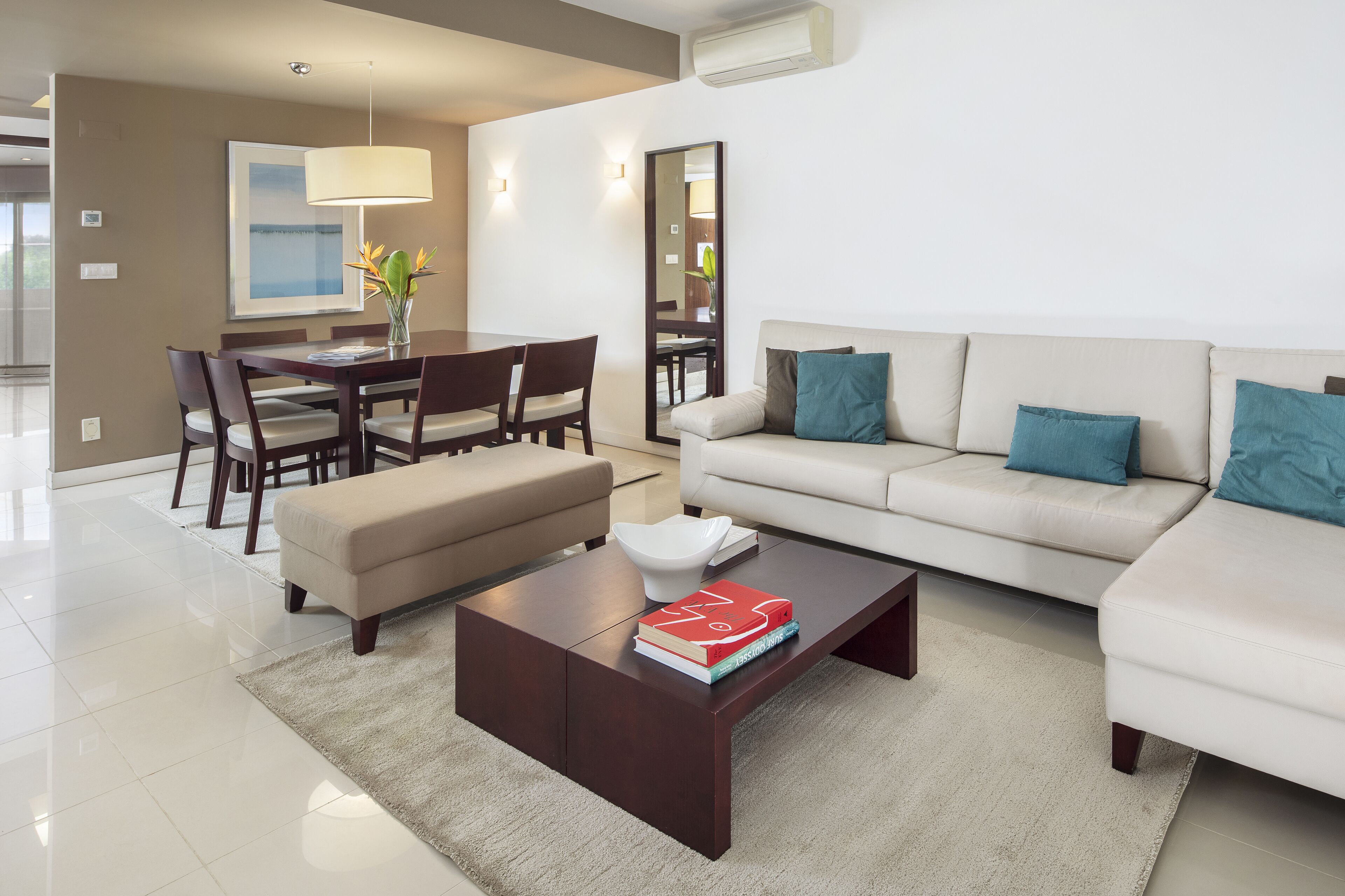 A modern living room with a dining area, a sofa set, and a coffee table with books.