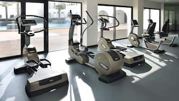 Una palestra con cyclette e tapis roulant, ampie finestre e vista sulla piscina.