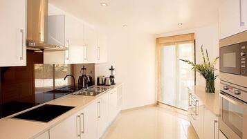 Una cocina moderna con armarios blancos, electrodomésticos de acero inoxidable y un ventanal grande.