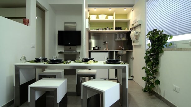 Una cocina moderna con una isla central, electrodomésticos integrados y un televisor de pantalla plana.