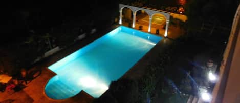 Una piscina con cubierta de baldosas y una estructura de pérgola.