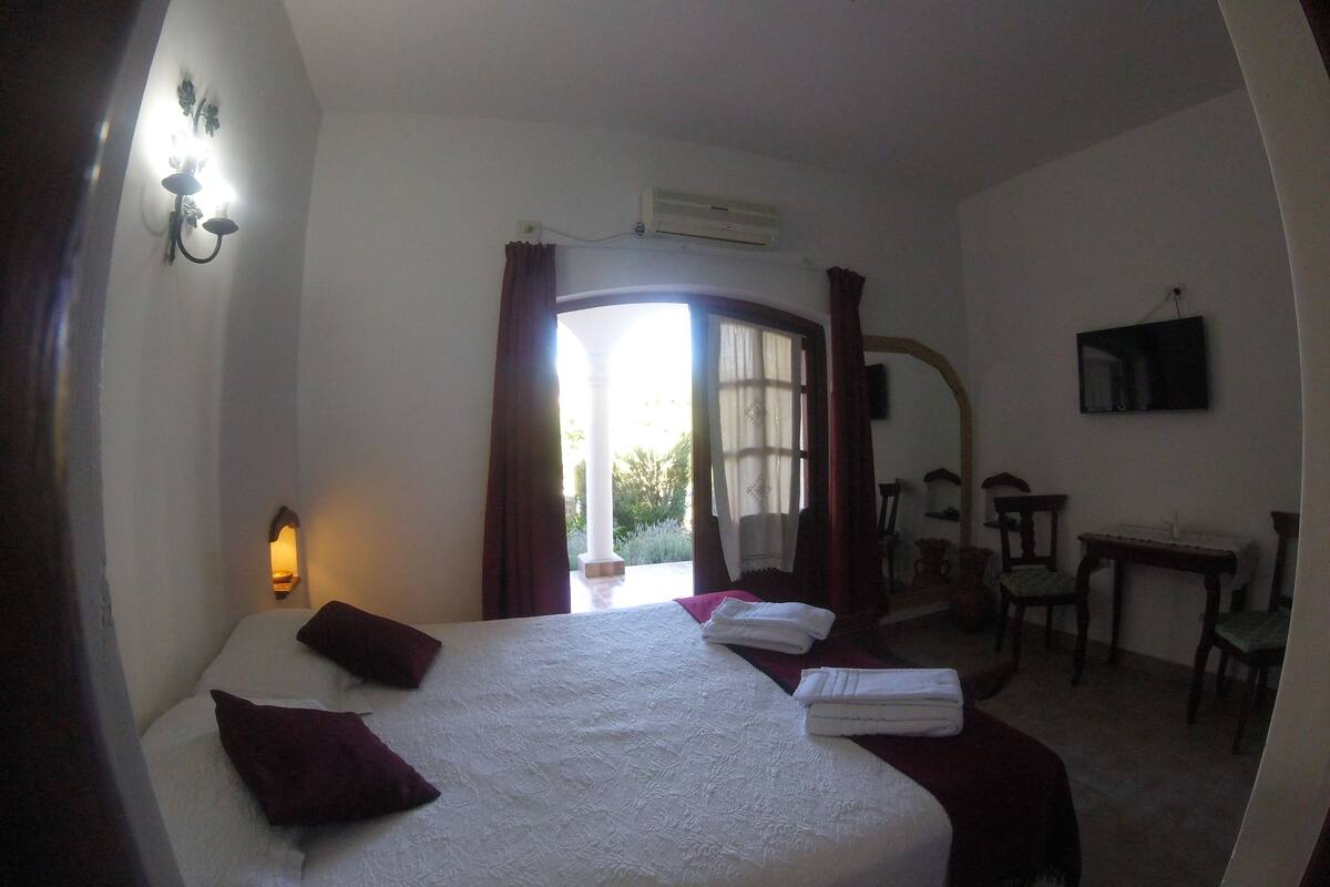 A hotel room with a bed, a desk, a chair, and a TV.