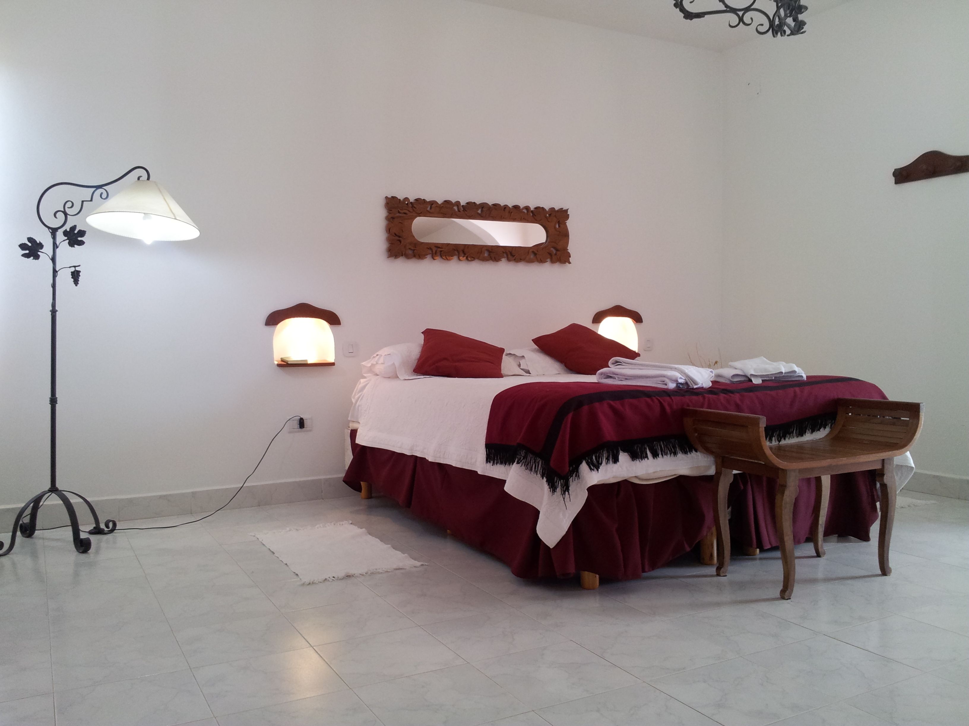 A bedroom with a bed, a chair, a floor lamp, and wall-mounted lights.