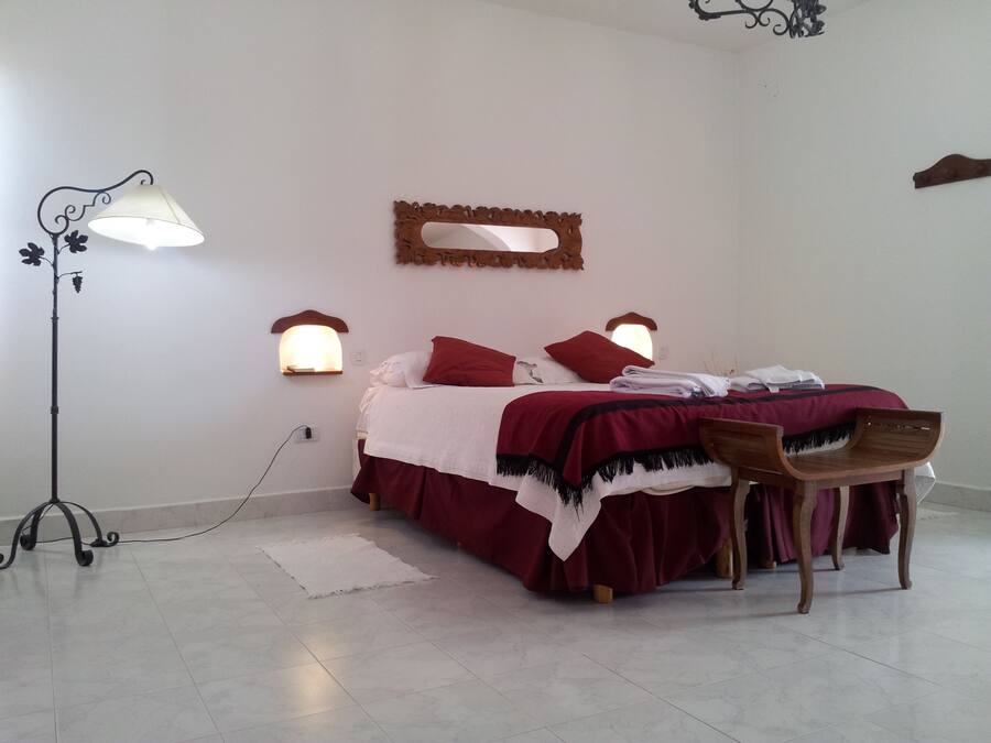 A bedroom with a bed, a chair, a floor lamp, and wall-mounted lights.