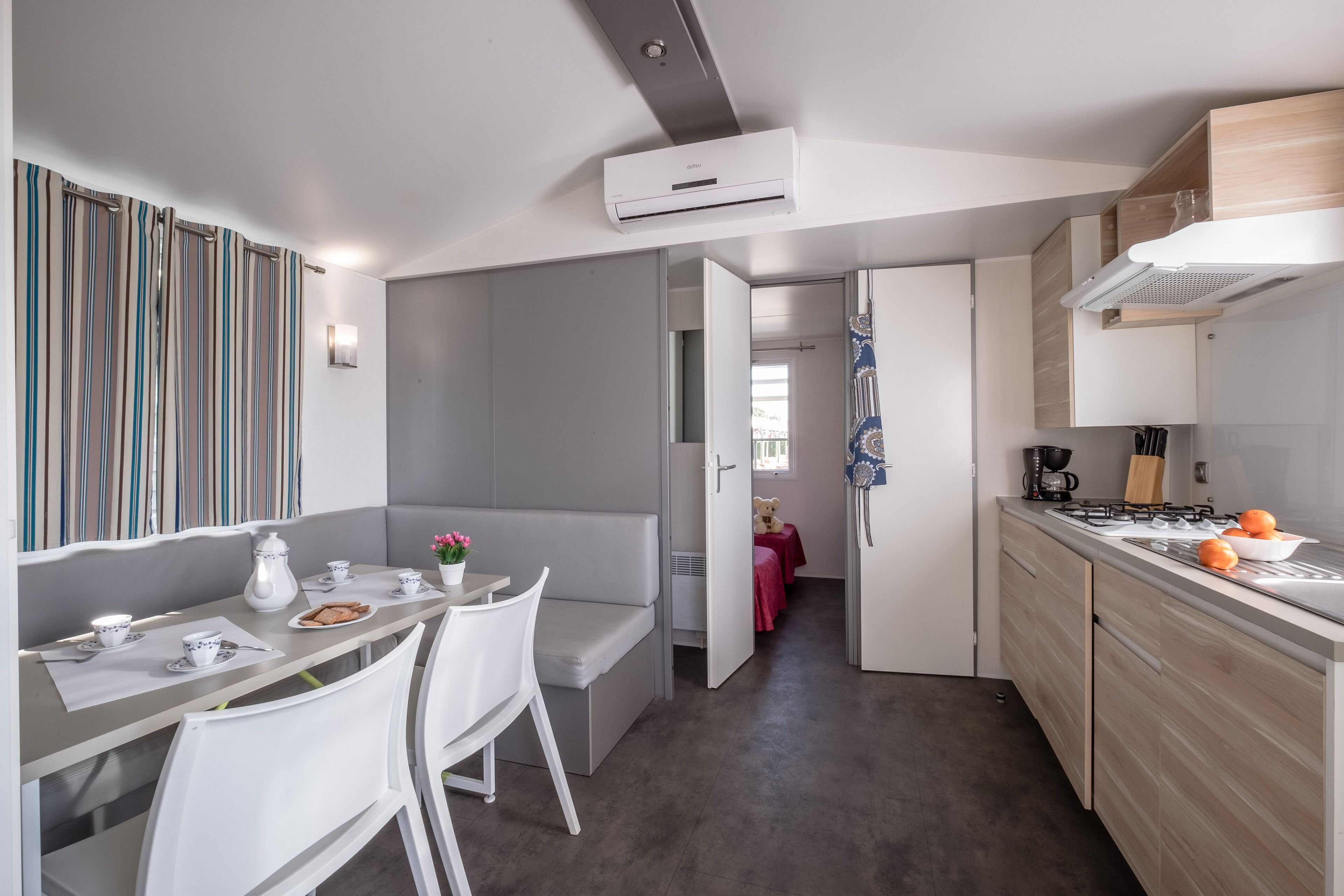 Une cuisine moderne dotée d’une cuisinière intégrée, d’un coin repas avec un banc et d’un rideau à rayures.