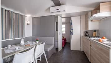 Une cuisine moderne dotée d’une cuisinière intégrée, d’un coin repas avec un banc et d’un rideau à rayures.
