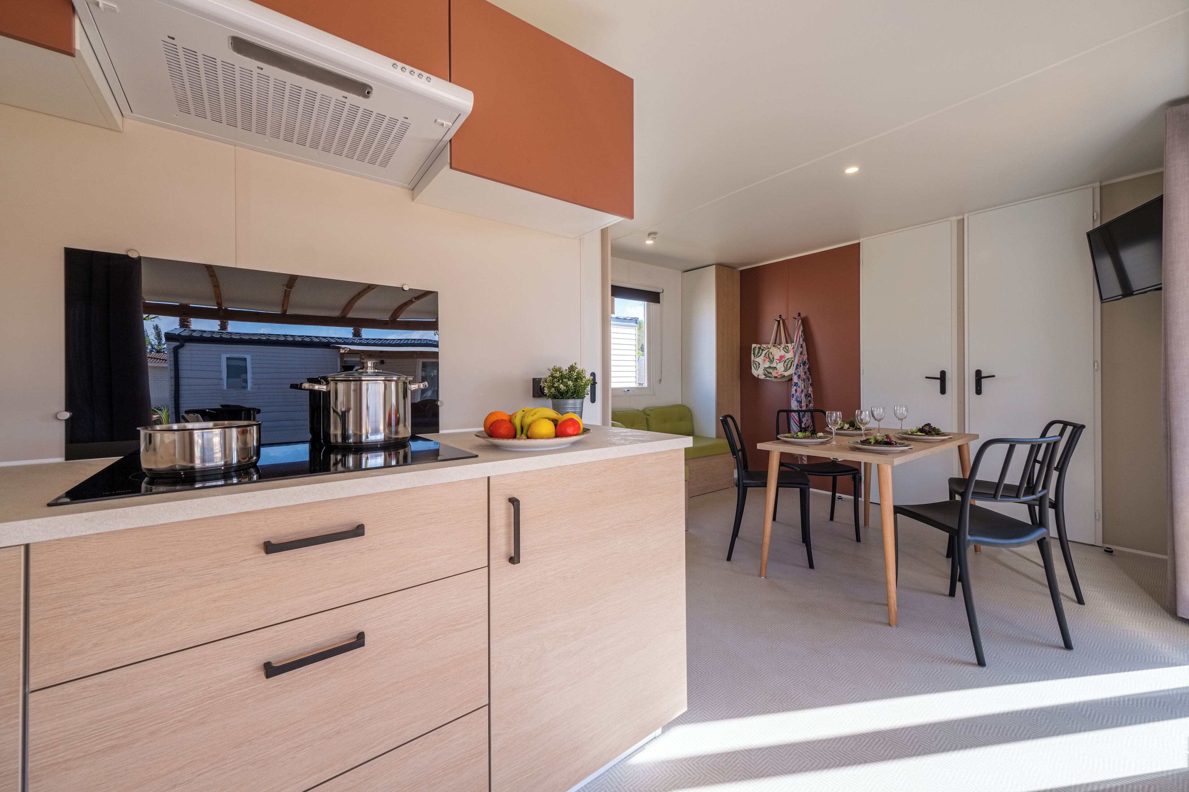 A modern kitchen with a dining area, featuring a stove, sink, and a table set for dining.