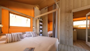 Une pièce en bois avec un lit, une étagère avec des serviettes et une porte donnant sur une autre pièce.