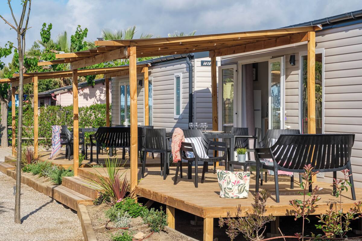 A covered outdoor patio with wooden furniture and a small garden area.