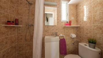 A bathroom with a shower, toilet, sink, and a mirror.