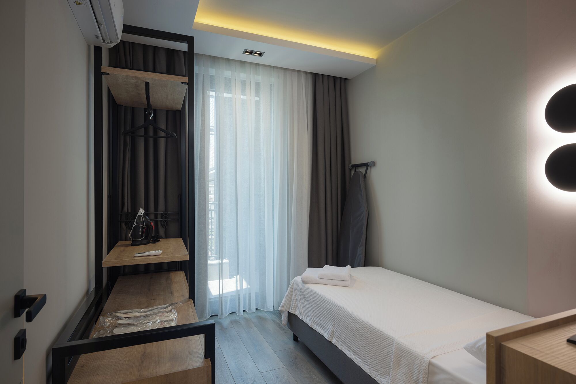 Una habitación de hotel moderna con cama, escritorio, silla y armario.