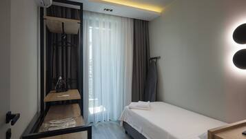 Una habitación de hotel moderna con cama, escritorio, silla y armario.