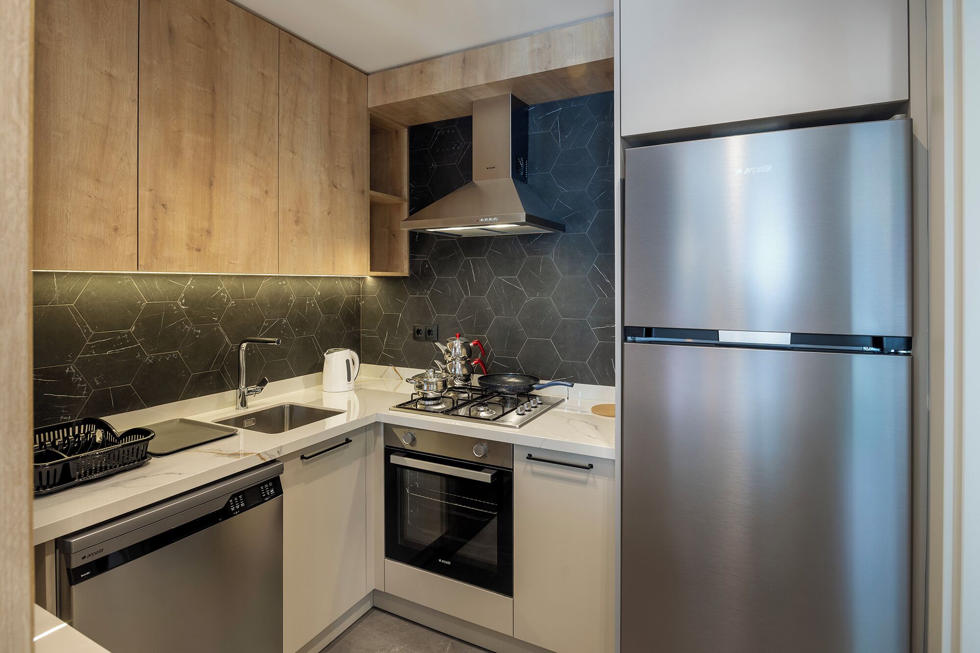 A modern kitchen with wooden cabinets, a stainless steel refrigerator, a gas stove, and a dishwasher.