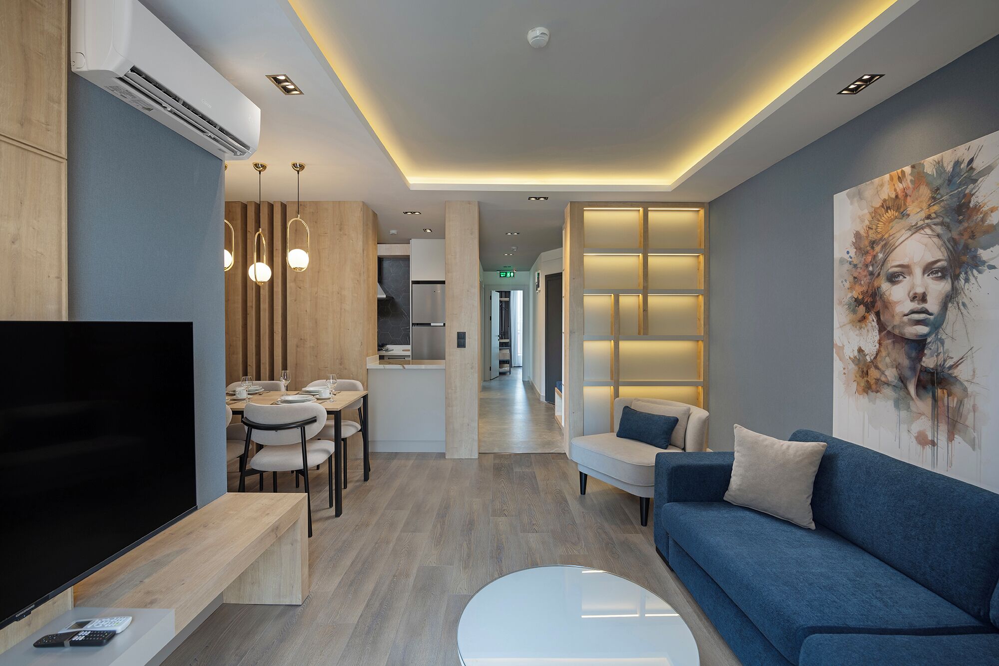 A modern living room with a flat-screen TV, a sofa, a coffee table, and a dining area with a table and chairs.