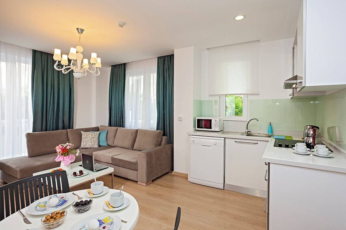 A modern living room with a sofa, dining table, and a kitchenette with a microwave and coffee maker.
