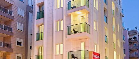 A multi-story hotel with balconies, a car parked in front, and a sign indicating a restaurant.