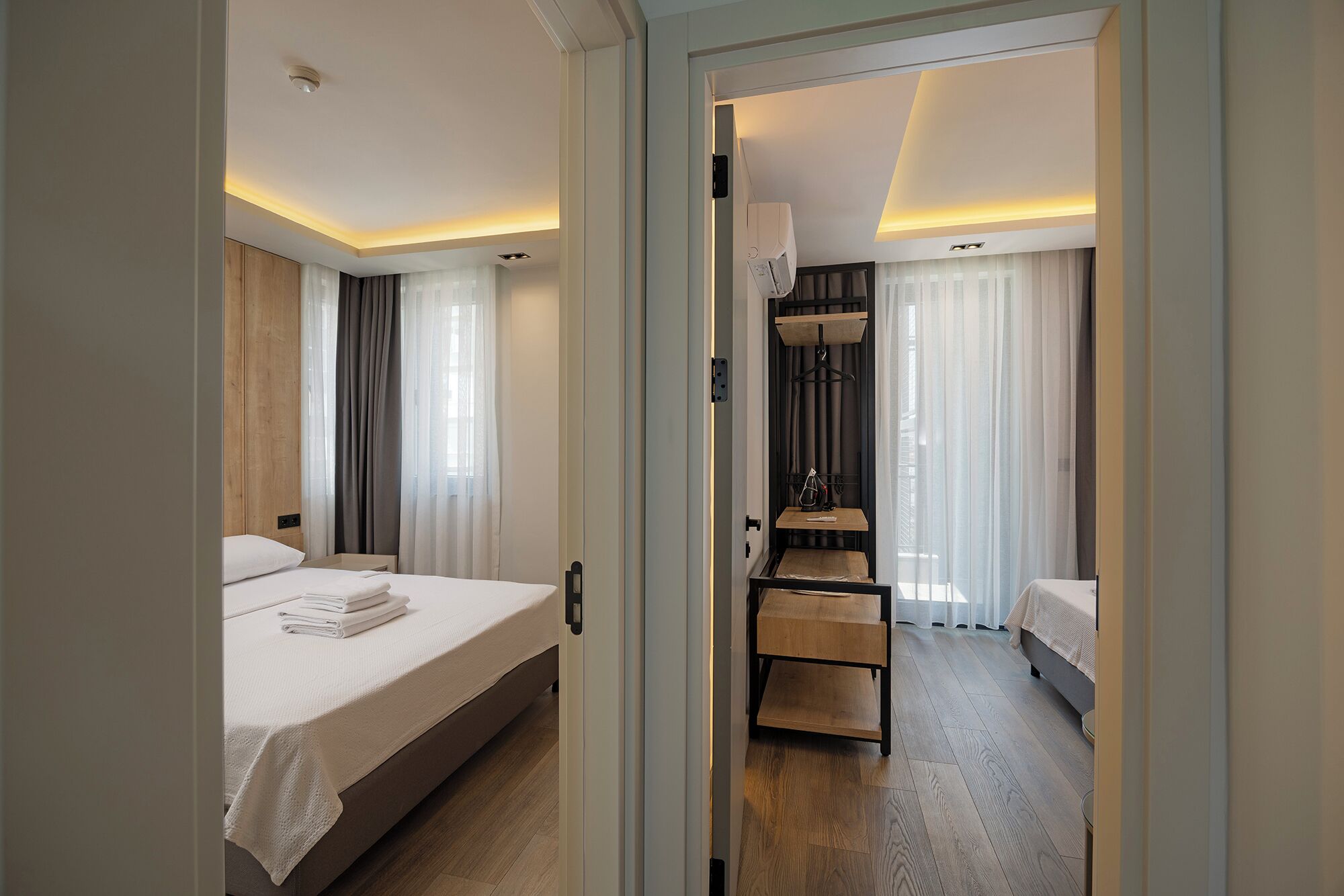A hotel room with a bed, a small table, a wardrobe, and a shower area.