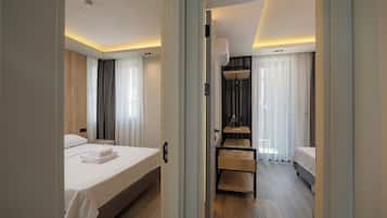 A hotel room with a bed, a small table, a wardrobe, and a shower area.