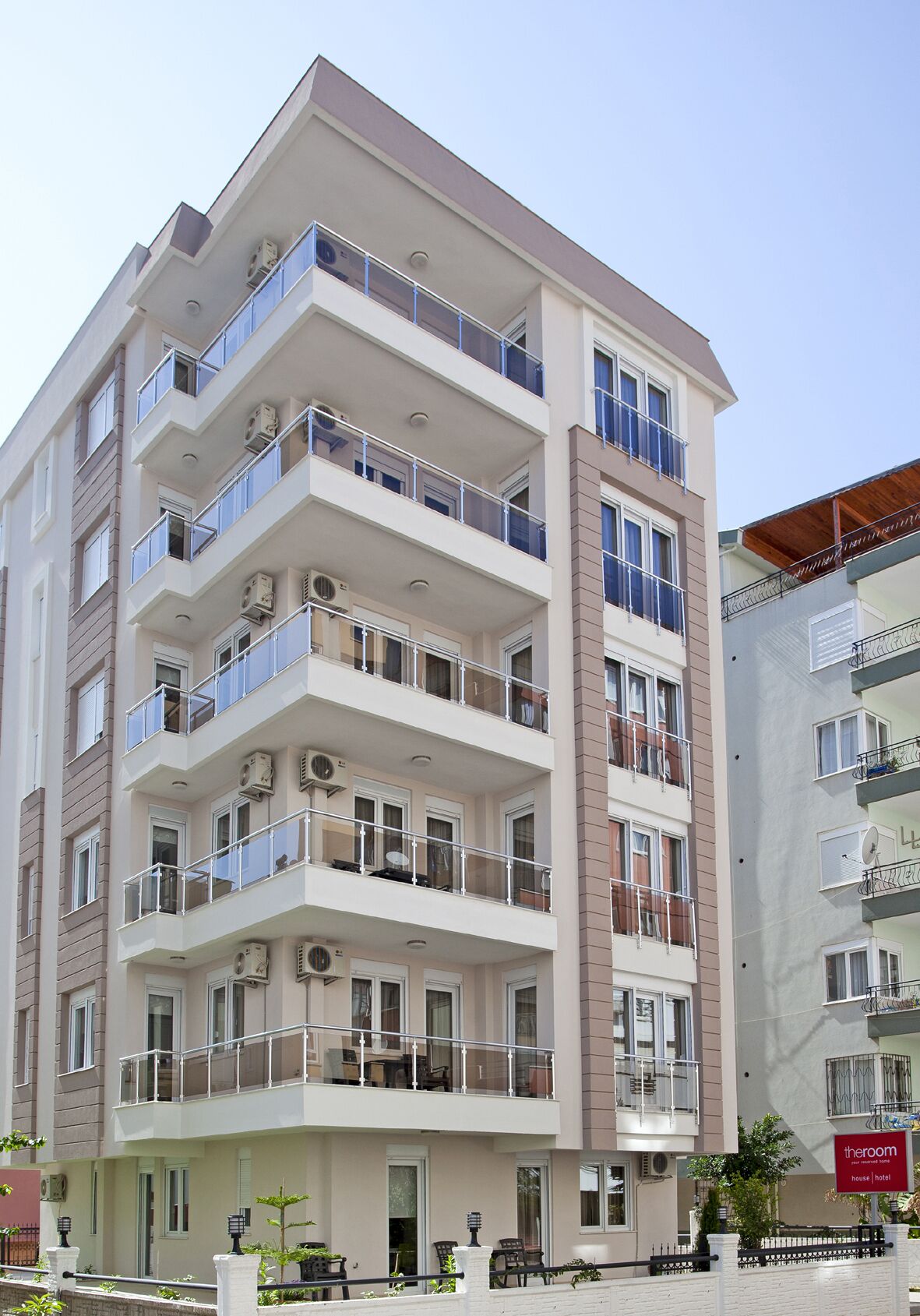 A multi-story hotel with balconies, air conditioning units, and a sign indicating it is a house and hotel.