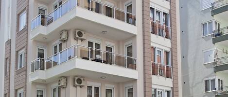 A multi-story hotel with balconies, air conditioning units, and a sign indicating it is a house and hotel.