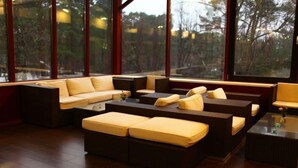 Een moderne woonkamer met een hoekbank, een salontafel en grote ramen met uitzicht op het landschap.