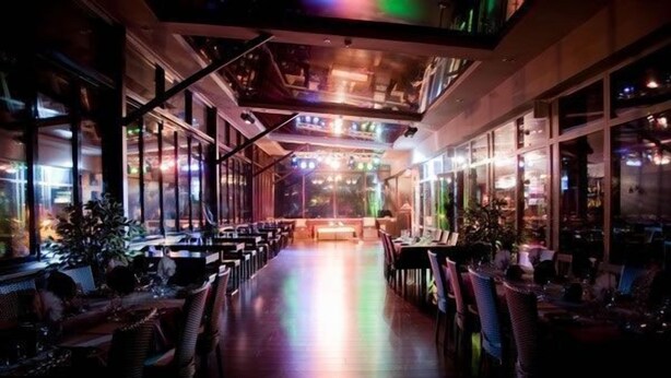 Een restaurant met een langwerpige indeling en hoge plafonds.