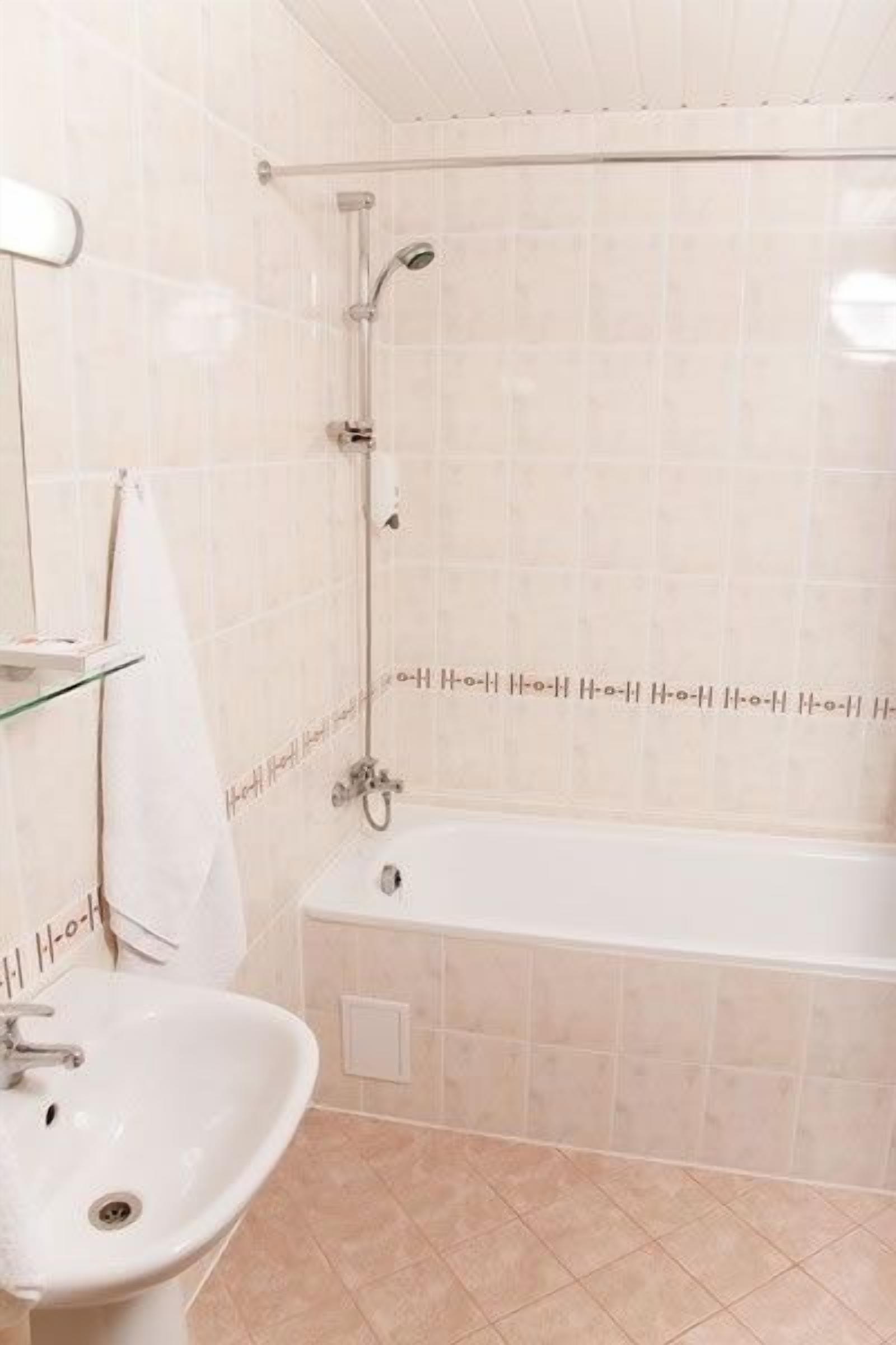 Un baño con una bañera, un lavabo y una estantería de vidrio.